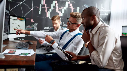 Person analyzing trading charts on multiple screens